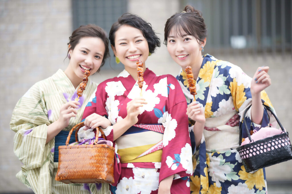 Japanese ladies wearing yukata and holding yakitori