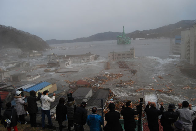 People watching tsunami waves sweep through a coastal town during the 2011 Japan earthquake disaster