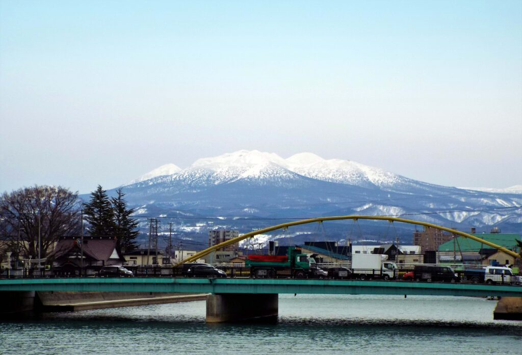 View of Aomori City with a bridge and snow-covered mountains in the background
