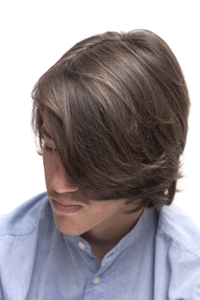 Medium-length men’s layered haircut with soft texture and natural movement through the ends