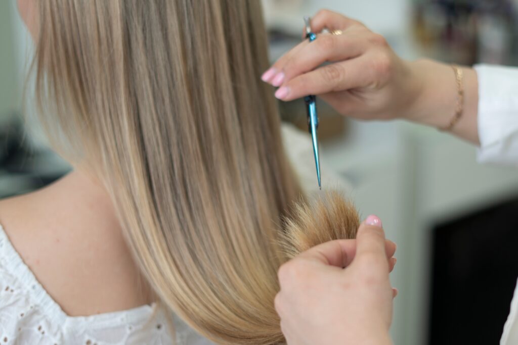 Hairdresser using point-cutting scissors vertically to soften the ends of long hair