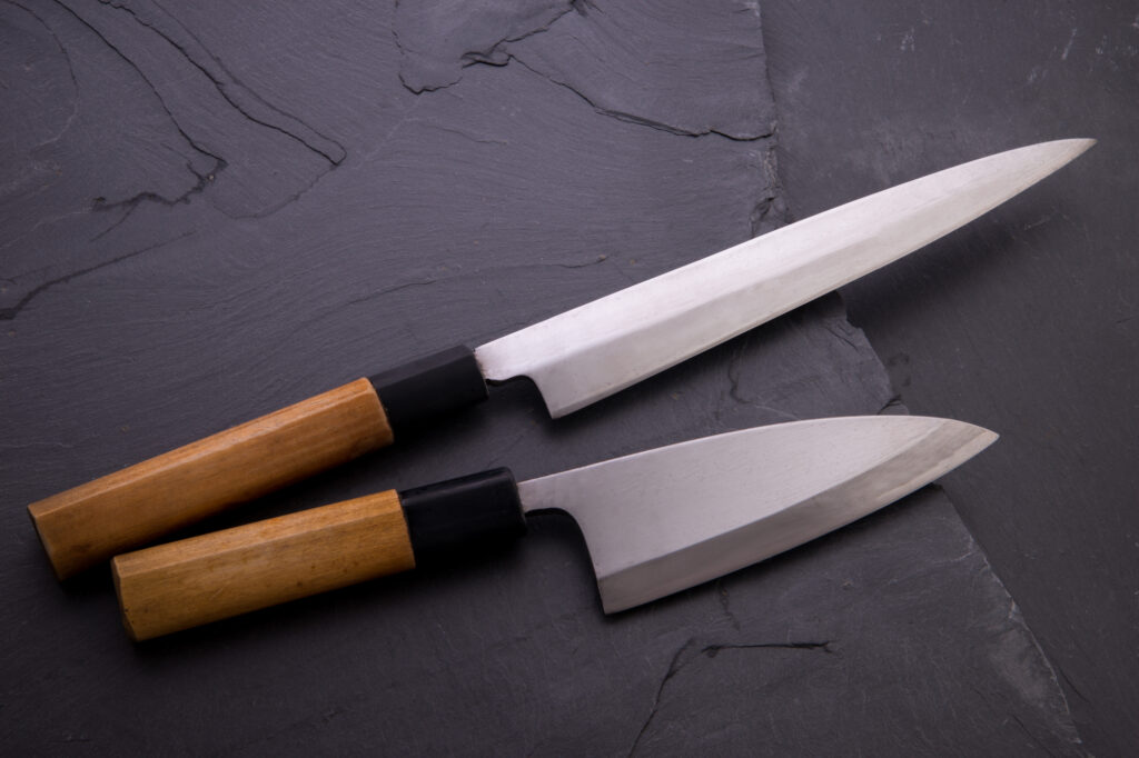 Close-up of a craftsperson polishing a sword blade on a wet sharpening stone.